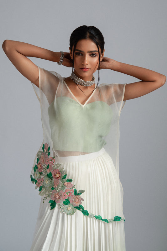 Organza top with delicate floral motifs, accompanied by a sage green bustier and an ombré-layered asymmetrical skirt. 