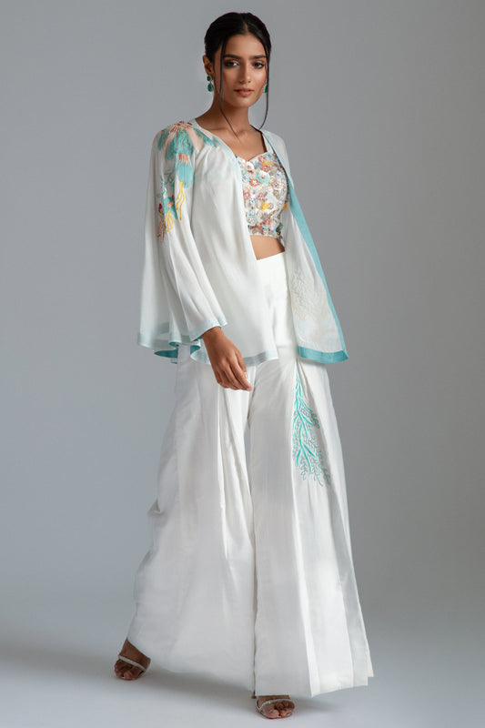 White asymmetrical jacket complemented by chanderi silk pleat flairs and a hand-embroidered net bustier.